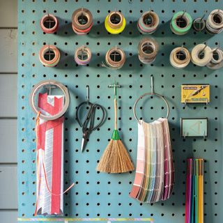 blue pegboard with colour charts, scissors, washi tape reels