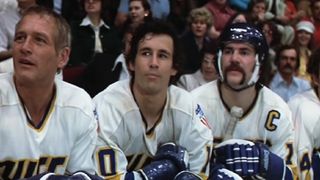 Hockey players watch from the sidelines in Slap Shot
