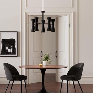 A black modern light fixture hanging above a dining table