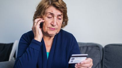 Senior woman using mobile phone while holding credit card