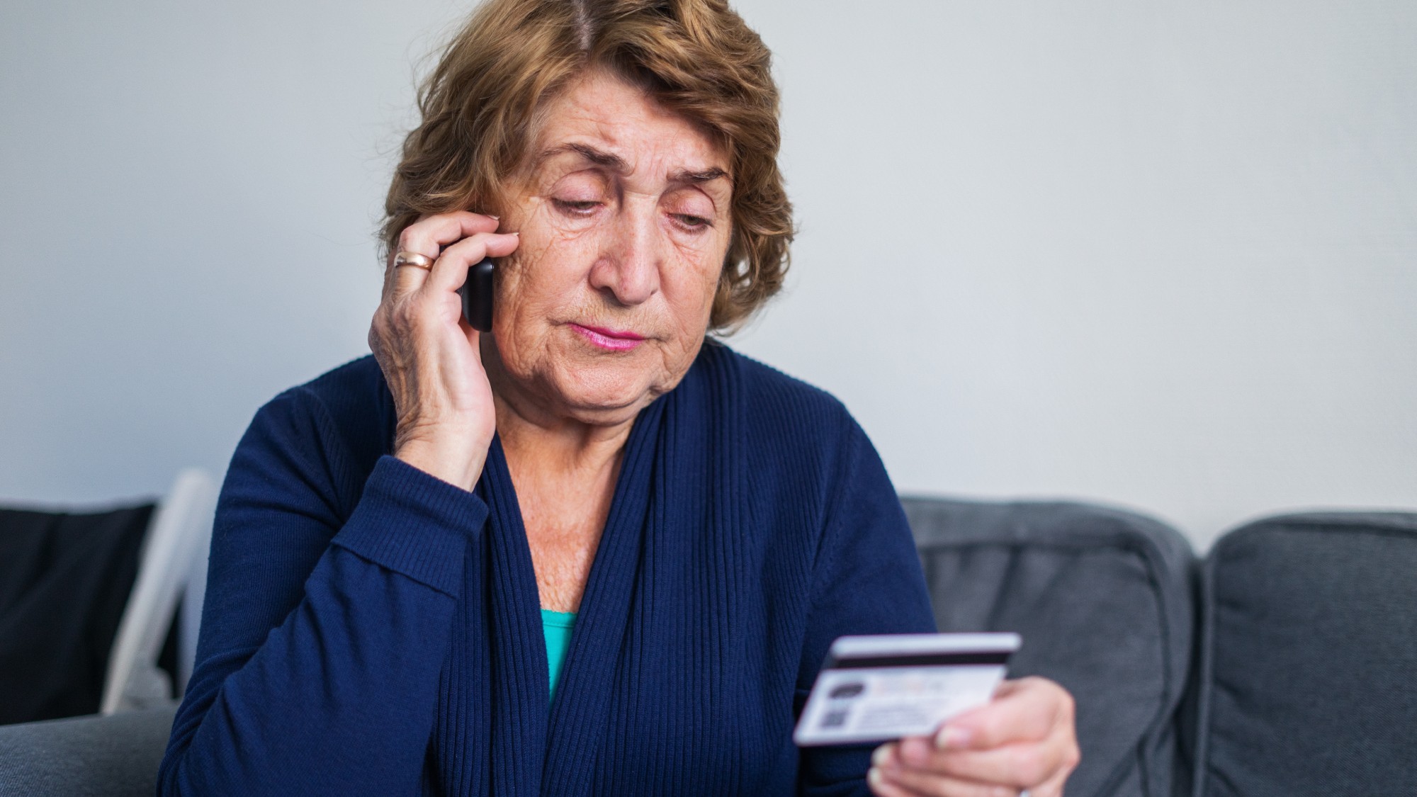 Senior woman using mobile phone while holding credit card