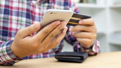 Young man hands holding credit card and using phone