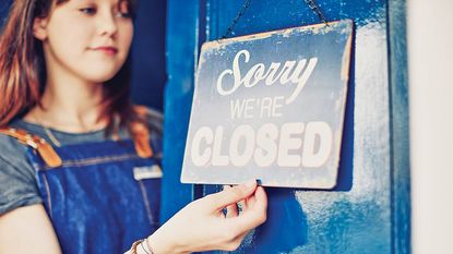Woman hanging "closed" sign on door
