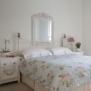 guest bedroom with rose patterned bedlinen and bedside cabinet