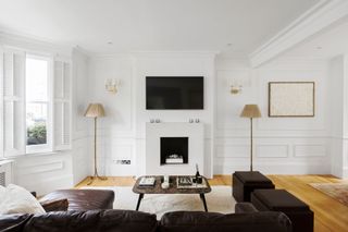 White living room with minimalist fireplace, black corner sofa, brown marble coffee table and white shutters