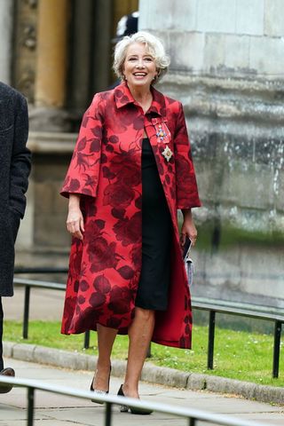 Emma Thompson wearing a red coat and black dress