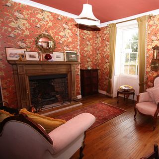 living area with pink ceiling and wallpaper wall and wooden floor and arm chair