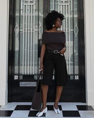 @daniellejinadu wearing black denim Bermuda shorts and an off-the-shoulder top