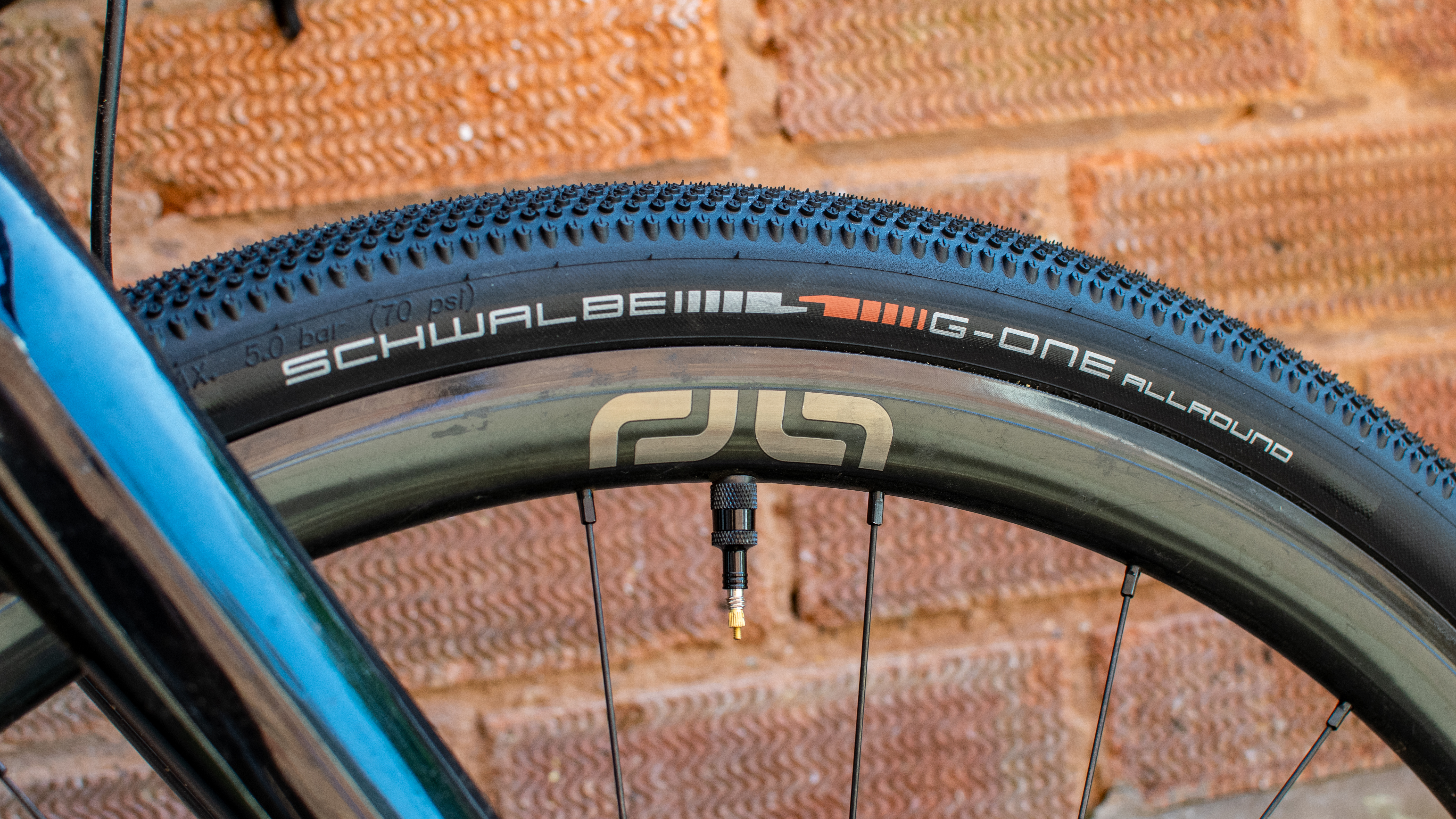 A Schwalbe G One All Round tyre in front of a brick wall 