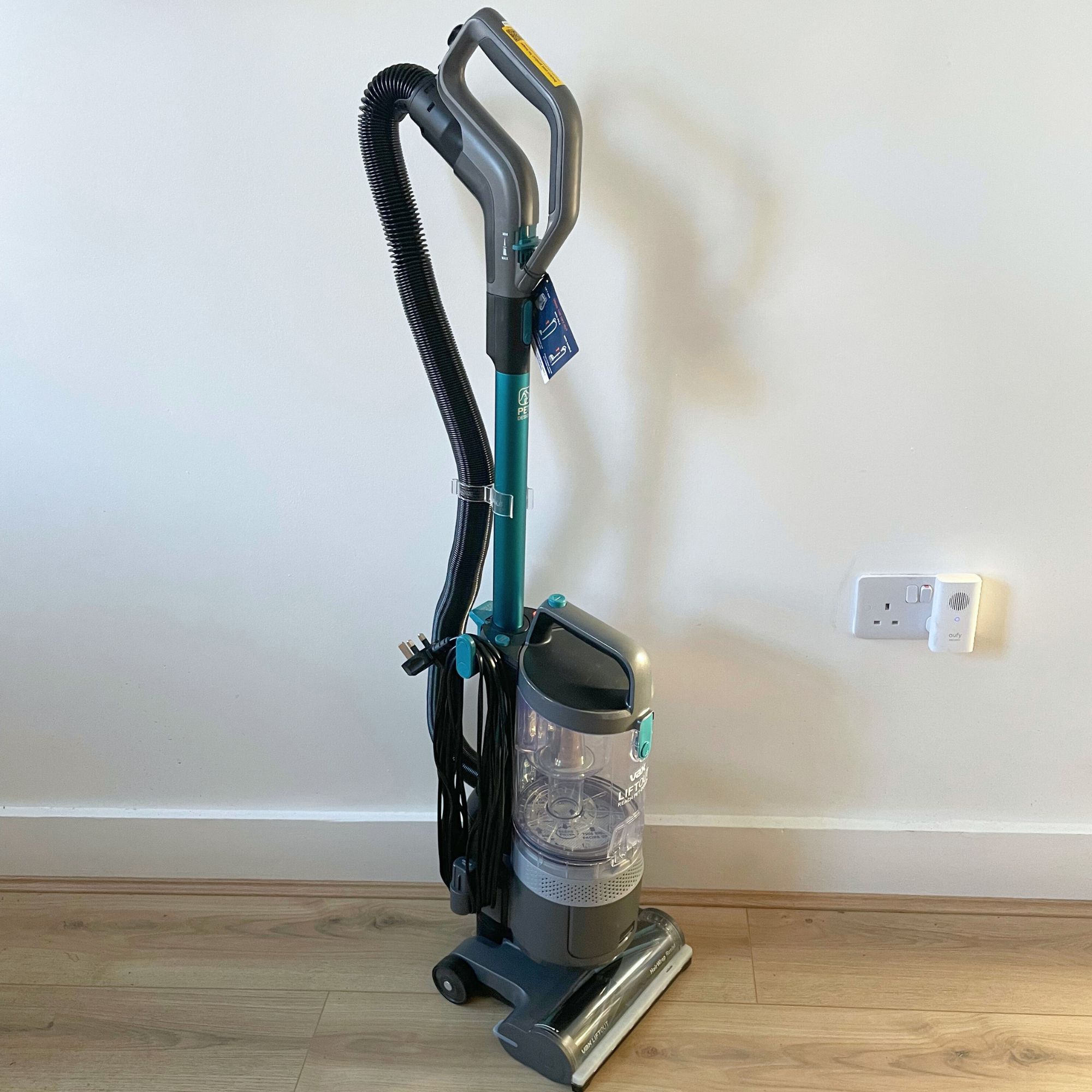 Assembled Vax LiftOut Reach Pet Design Vacuum Cleaner on wood-effect flooring in front of a white painted wall