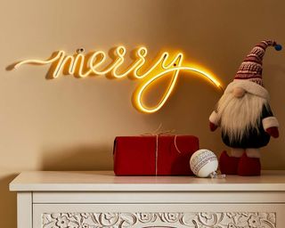 merry letter light sign on a chest of drawers with a Scandi Santa by dunelm