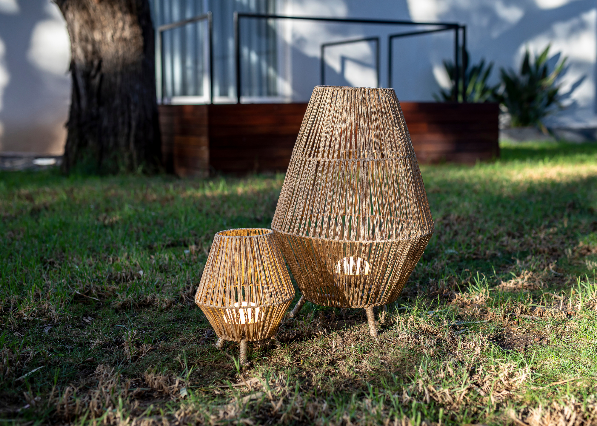 A set of two woven outdoor lamps in a garden
