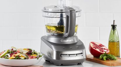 A Cuisinart 10-cup food processor in grey on the countertop with vegetables and oil around it