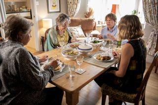 A scene from Beyond Paradise showing Anne (Barbara Flynn), Martha (Sally Bretton), Humphrey (Kris Marshall) and Martha's nan (Anne Lester) sitting around the table for lunch. Humphrey has been put in a smaller chair and the table comes up to his armpits.