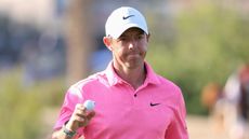 Rory McIlroy holds his ball up in a show of appreciation to the crowd while wearing a bright pink Nike top