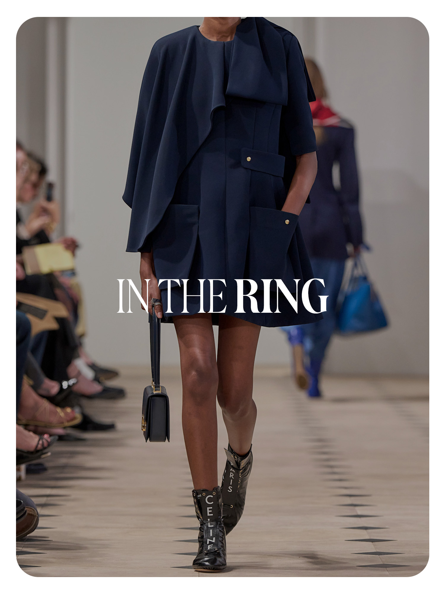 A Celine model walking in a runway show wearing a short coat with high-top black leather boxing sneakers that say Celine on them in white letters. Text reads, &quot;In the Ring.&quot;