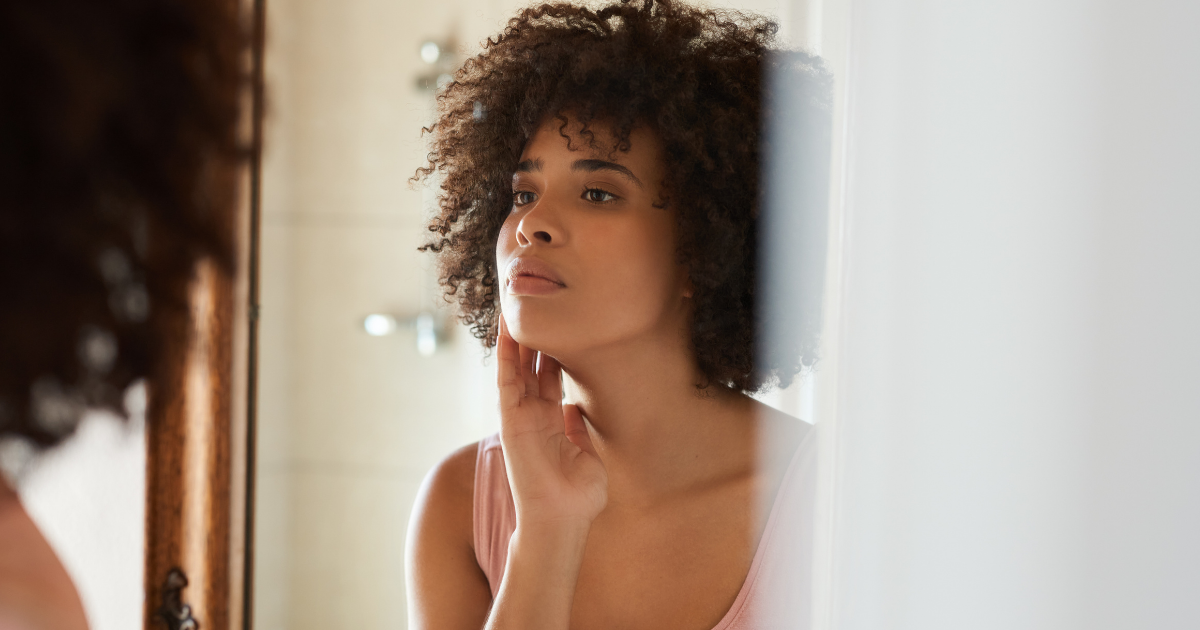 Beef tallow skincare -woman examining her skin in a bathroom mirror