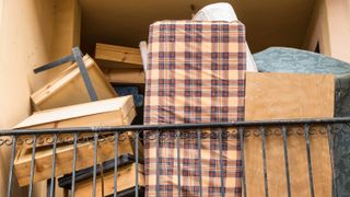 A mattress stored amongst boxes upright against railings