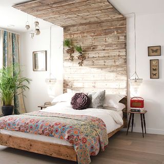 bedroom with white wall and wooden floor and wooden headboard