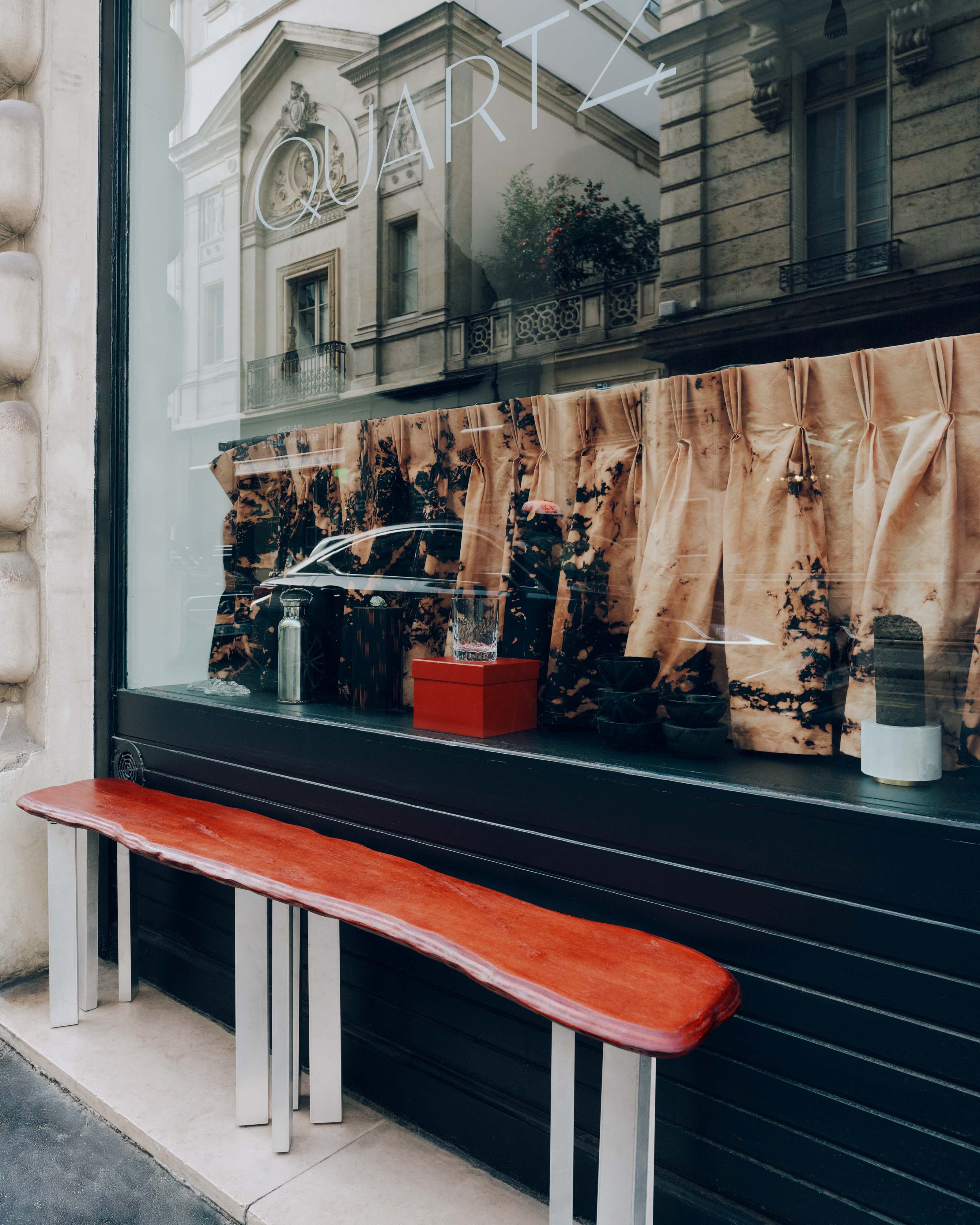 A coffee shop decorated with reflective, organically shaped chrome decor, brown curtains and wooden panels, and ceramic plates.