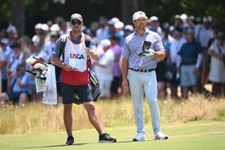 Bryson DeChambeau speaks to his caddie