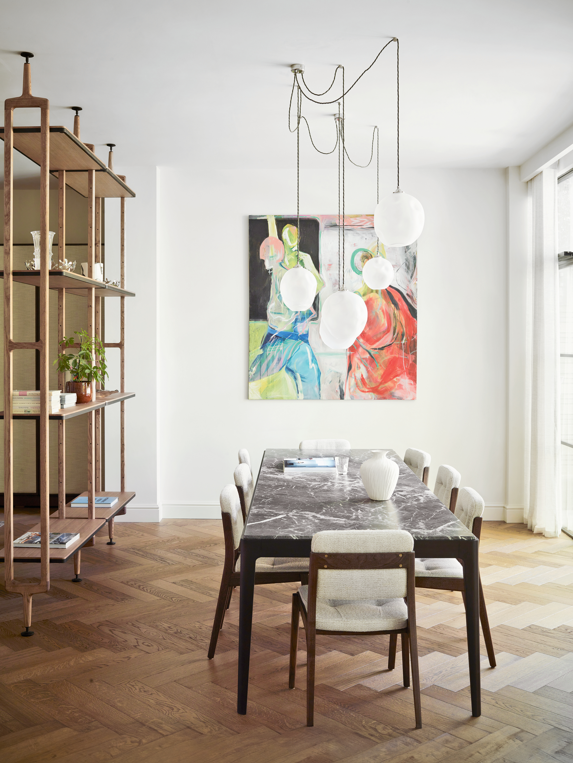 Dining area with parquet floor, freestanding shelving unit, grey marble table and cream and wood dining chairs