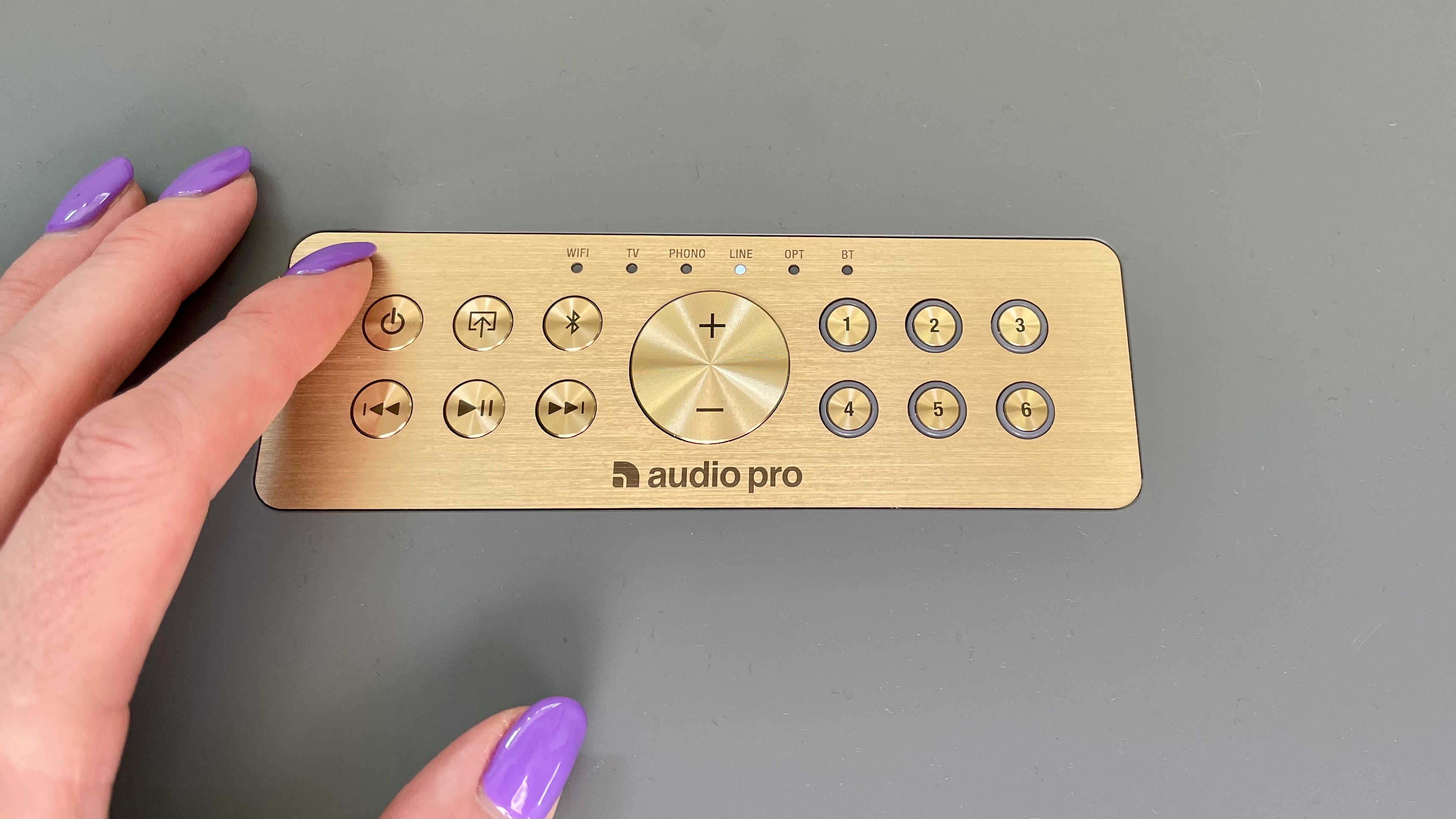 Audio Pro C20 top-plate closeup, with a hand pressing one of the buttons