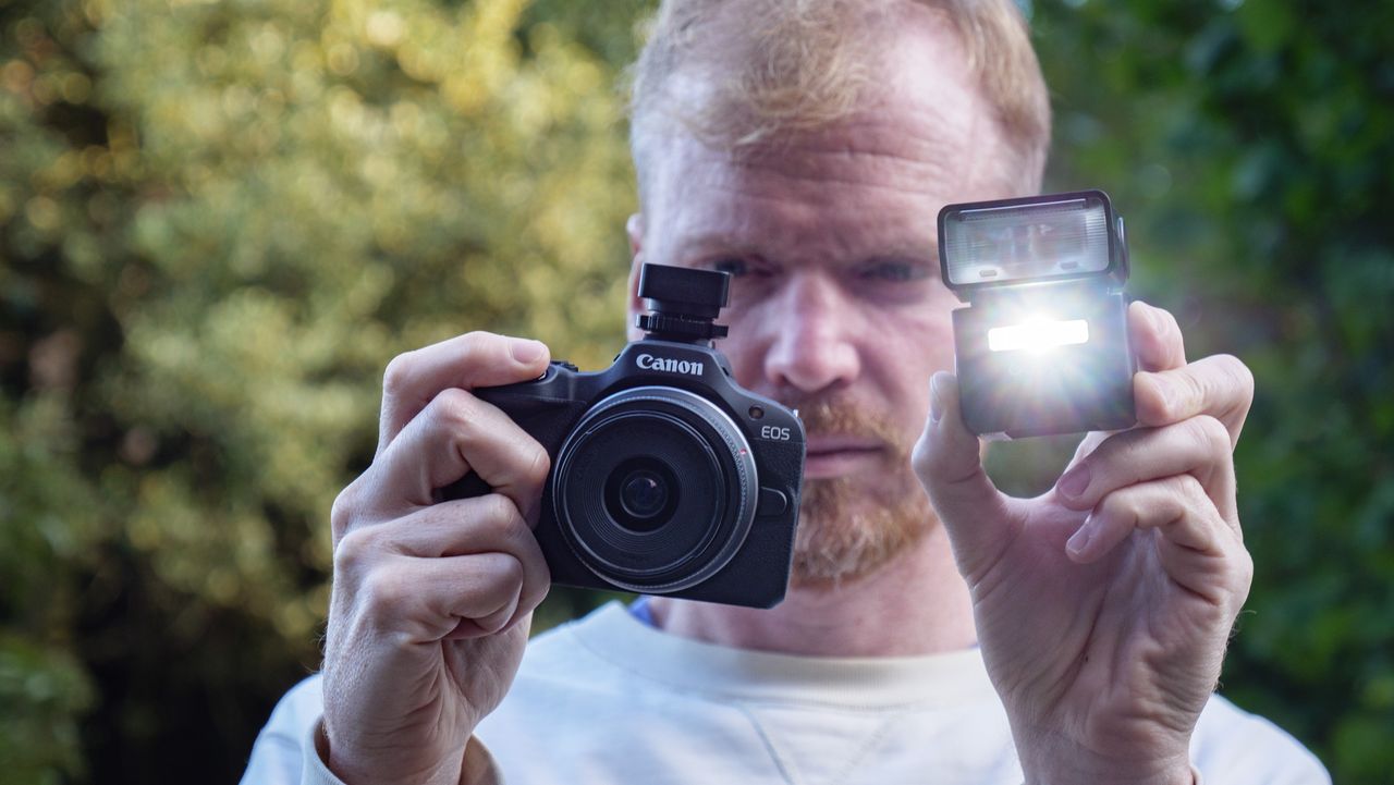 Godox iT32 camera flash alongside a Canon camera, held by photographer and TechRadar's Cameras Editor Tim Coleman,