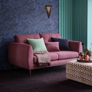 carpet colour trends for 2023, living room with aubergine carpet, pink sofa, blue marble effect wall, check footstool, view to garden