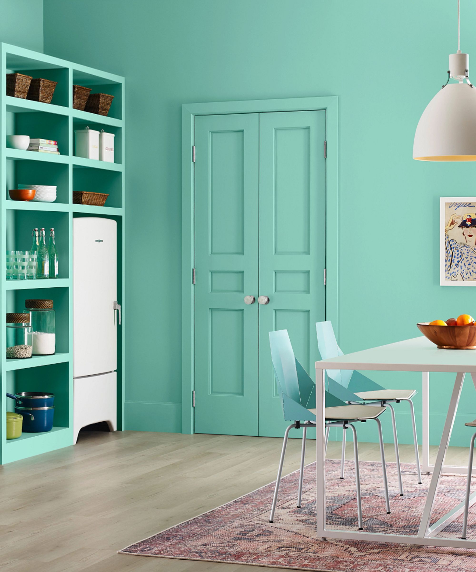 a dining room painted in Aquastone by Sherwin-Williams with a storage wall, white dining table and ceiling light, purple pink red and blue dining chairs