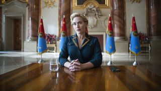 Kate Winslet sitting at a table in The Regime