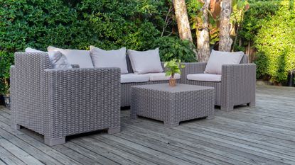 Large terrace patio with rattan garden furniture in the garden on wooden floor.