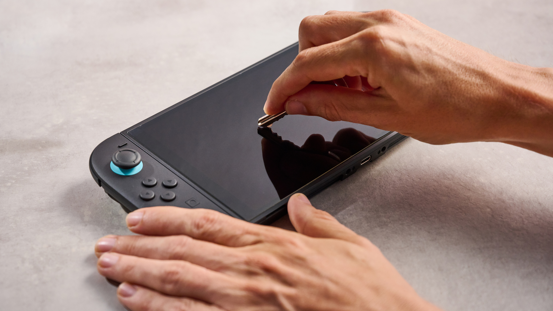 A man attempts to scratch the Belkin Tempered Glass Anti-Reflective Screen Protector after it has been applied to the Nintendo Switch 2.