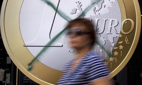 A woman walks by a crossed-out Euro advertisement in a Madrid shop