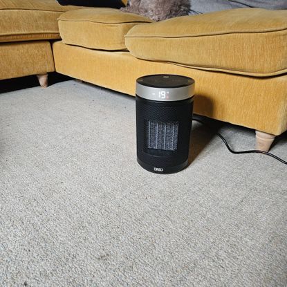 dreo fan heater turned on next to yellow sofa in living room