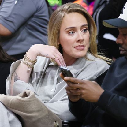 Adele attends a basketball game while wearing a gray matching set and white flats