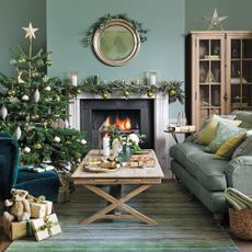 living area with teal wall and christmas tree with gifts and fireplace and sofa