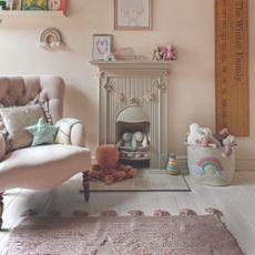 A pink kids' playroom with a central pink tasselled rug with stars and a pink armchair next to it