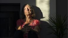 An older woman looks relieved as she leans her head back while sitting in the sun.