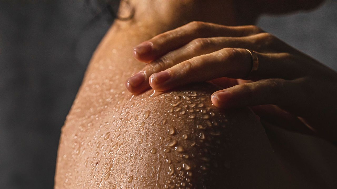 Woman&#039;s shoulder in the shower with water droplets on it - L&#039;Occitane Almond Shower Oil