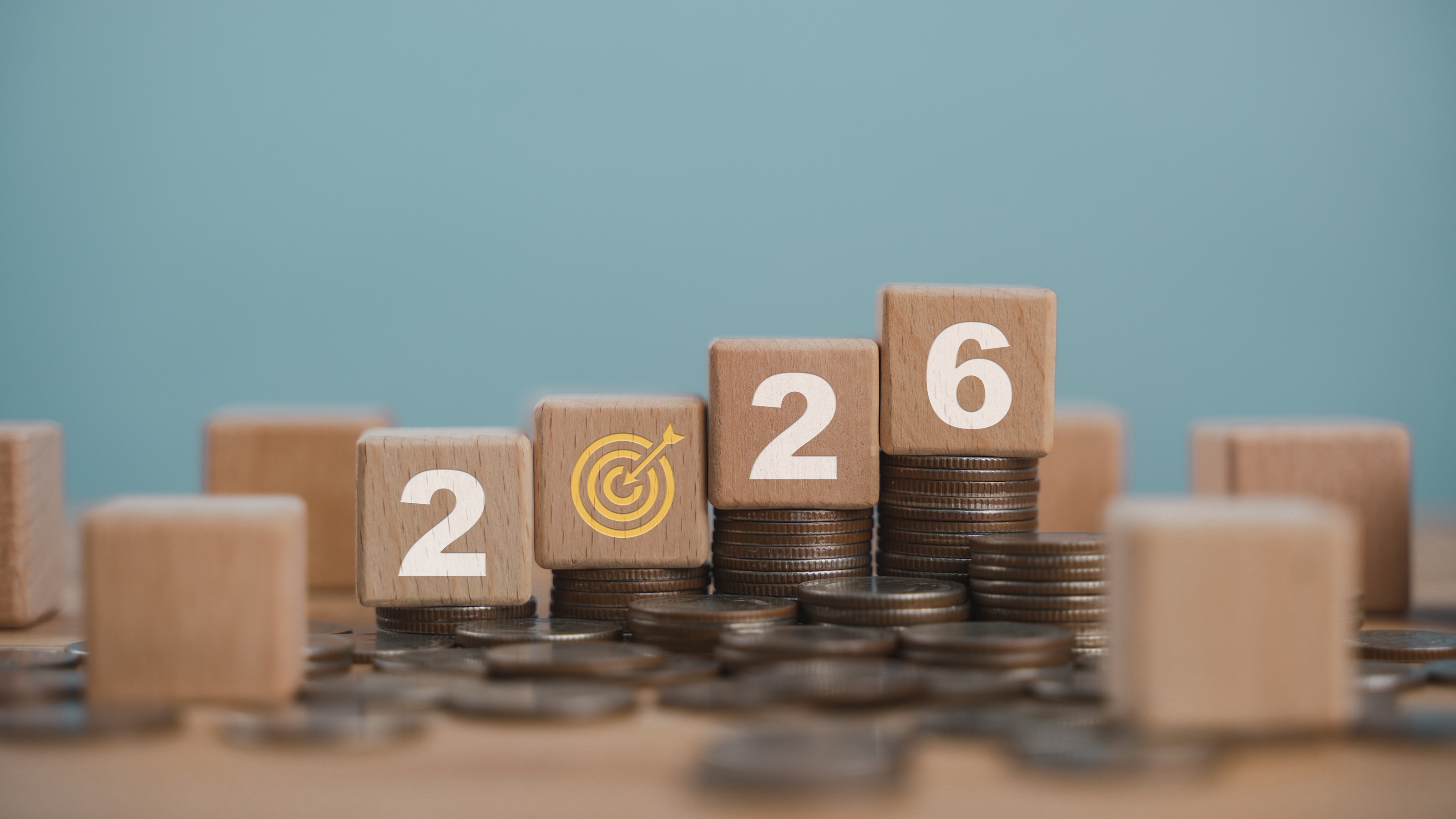 Blocks that say 2026 surrounded by scattered coins and stacks of coins.