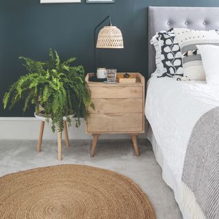 Bedroom with pale grey (griege) carpet and navy wall, with rug, bedside table and bed