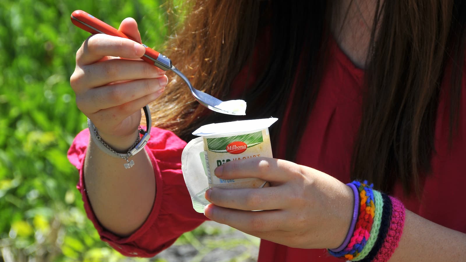 A woman putting a spoon into yoghurt