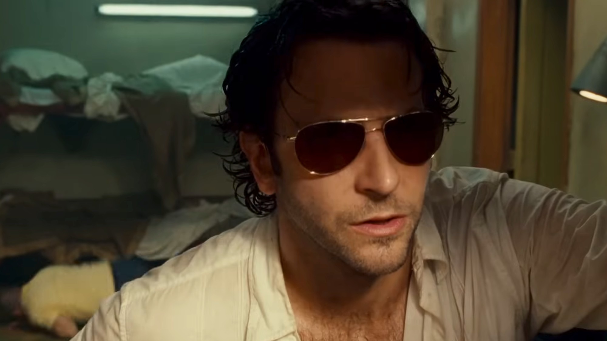 Bradley Cooper looking out of a window, wearing sunglasses and looking very rough in The Hangover Part II