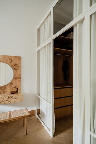 walk-in closet with glass wall and curtain covering, with burl vanity and rattan seat