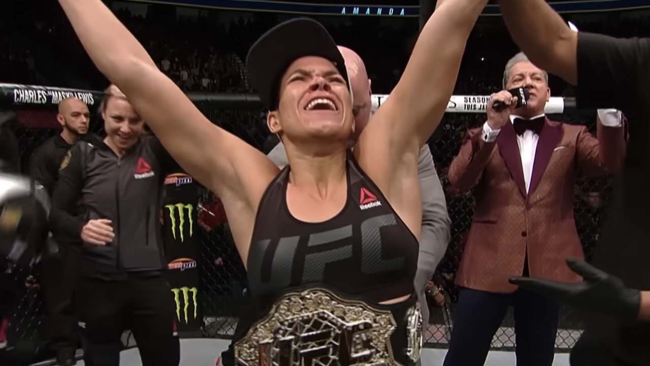 Amanda Nunes raising arms in victory after winning UFC belt from Ronda Rousey
