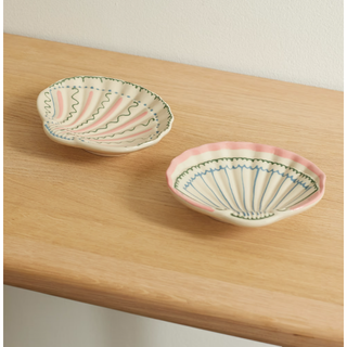 two ceramic dishes in the shape of seashells with wiggle line handpainted detail
