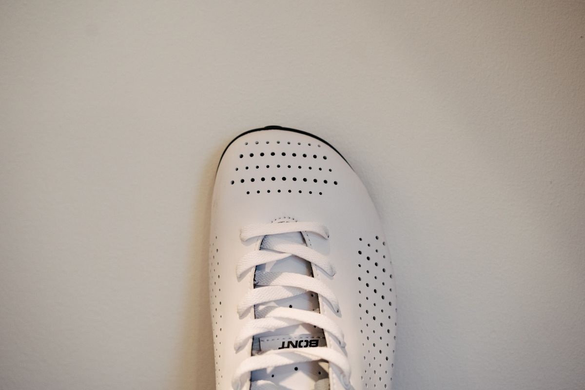 A lace up set of bike shoes on a wooden shelf