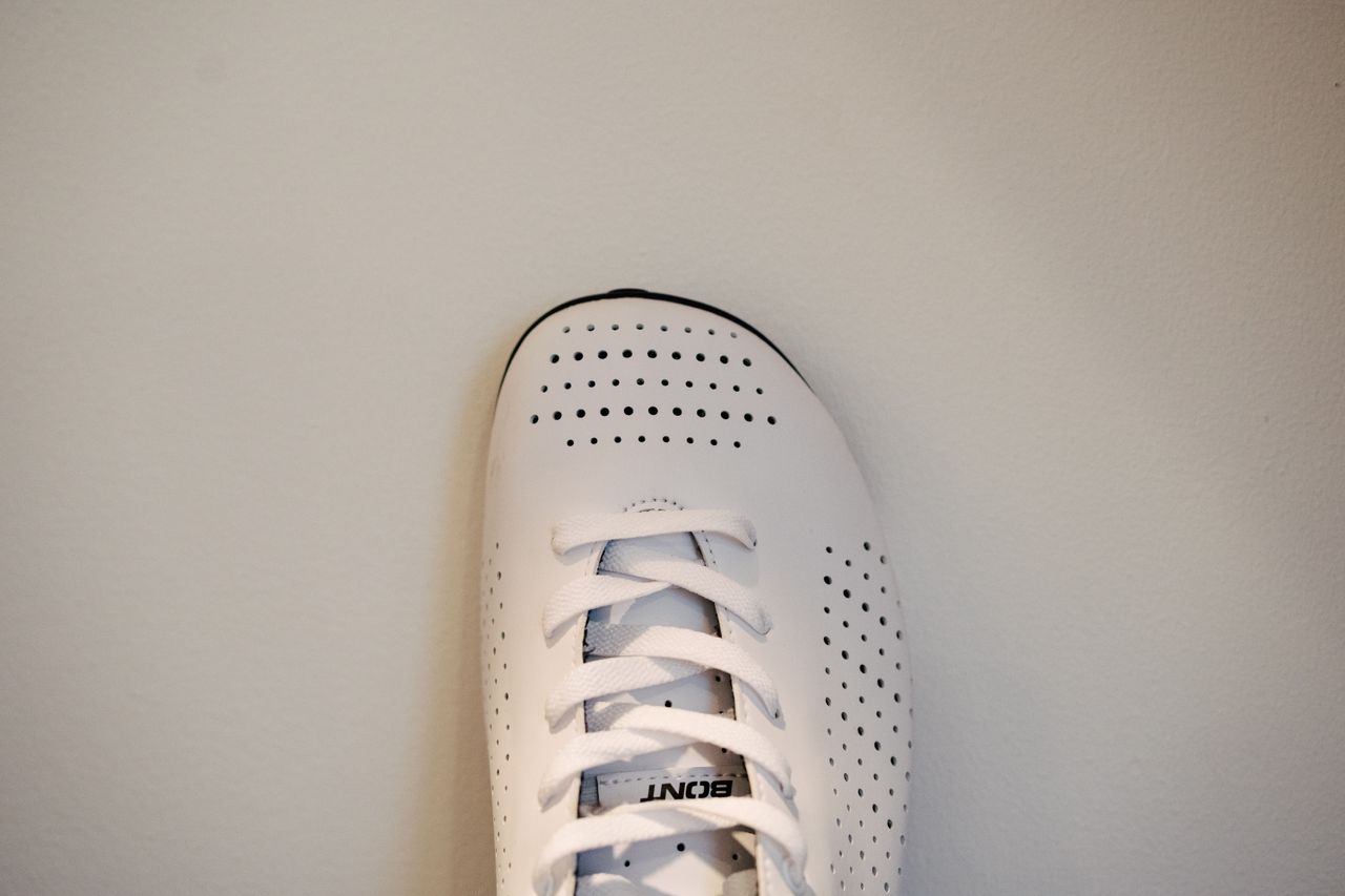 A lace up set of bike shoes on a wooden shelf