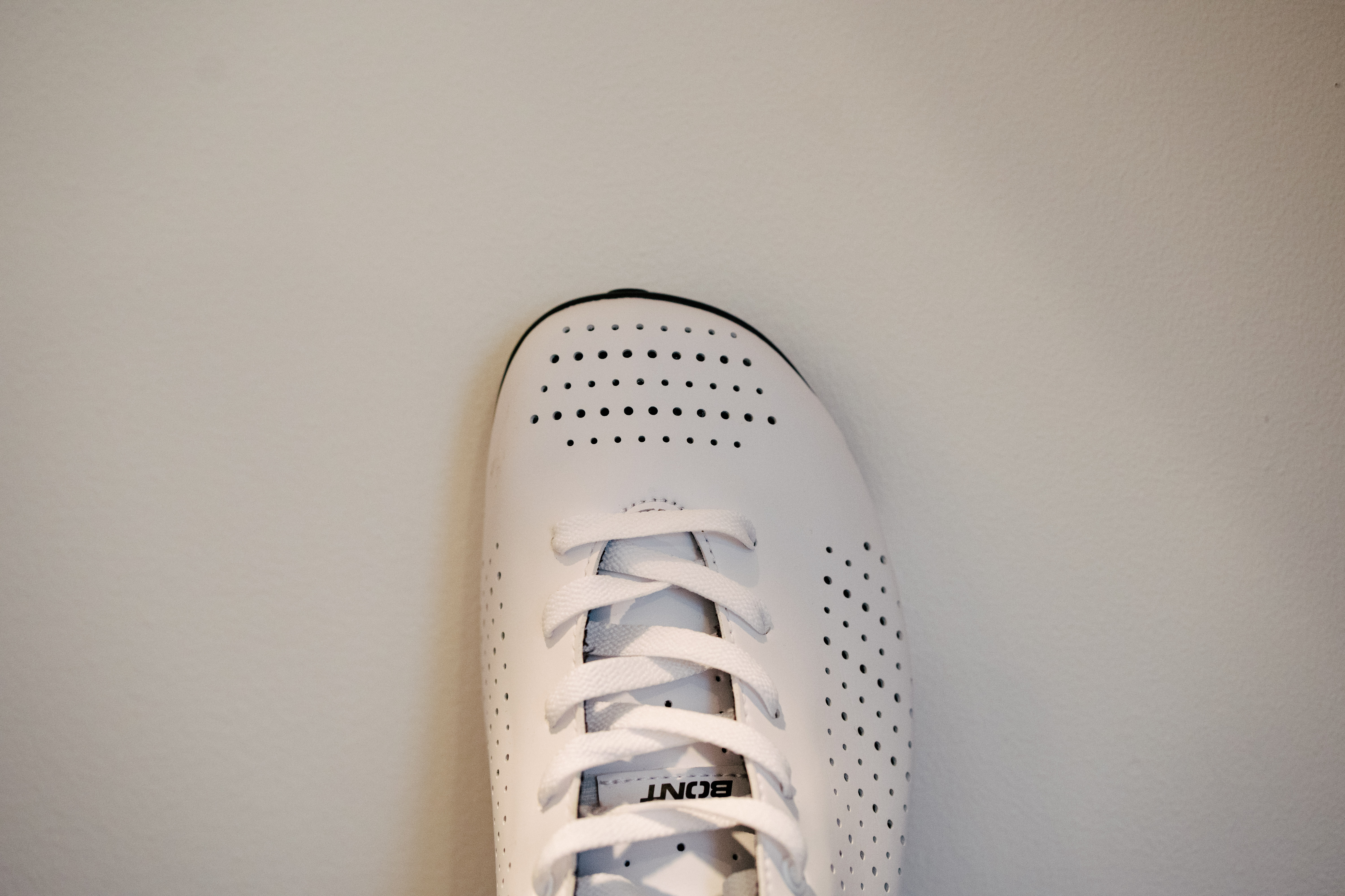 A lace up set of bike shoes on a wooden shelf